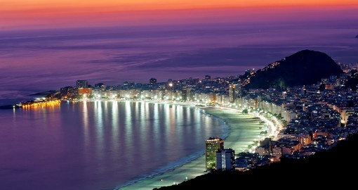 See the bright lights of Rio reflected in the ocean by Copacabana on yoru Brazil Tour
