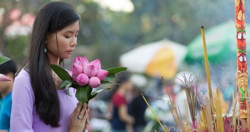Young Vietnamese woman offering flowers at Buddhist shrine