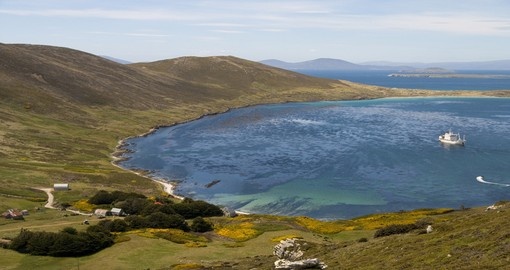 An idyllic bay in the Falkland Islands with a farmhouse and cruise ship