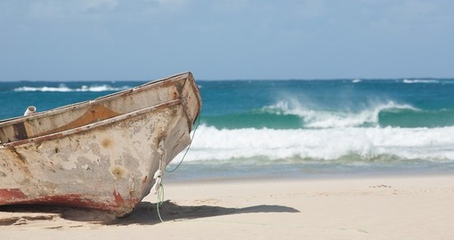 Old fishing boat on the beach. The waves of the Indian Ocean breaking on the beach of Barra in Mozambique
