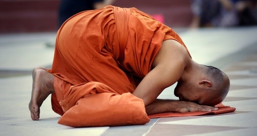 Buddhist monk kneels down in prayer