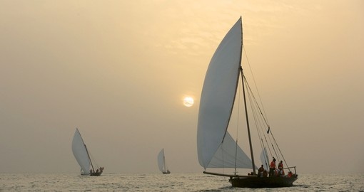 Traditional Dhows sailing in the Arabian Gulf, off Dubai, at sunset