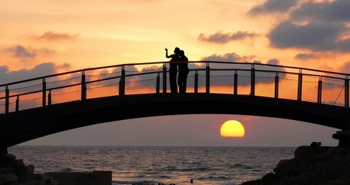 Silhouettes of two people standing on a bridge